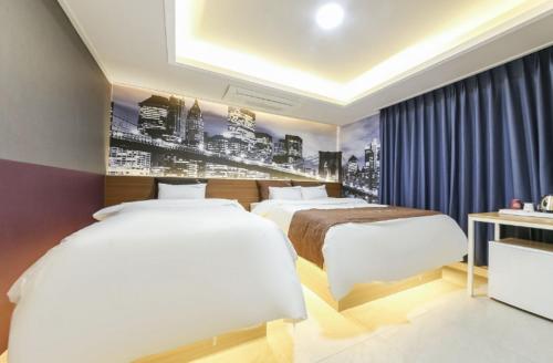 a hotel room with two beds and a painting on the wall at Gwangju Yeogijoa Hotel in Gwangju