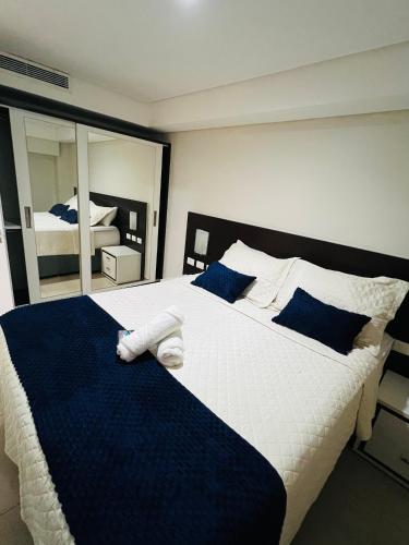 a bedroom with a large bed with blue and white sheets at Marinas Praia Flat 005 in João Pessoa