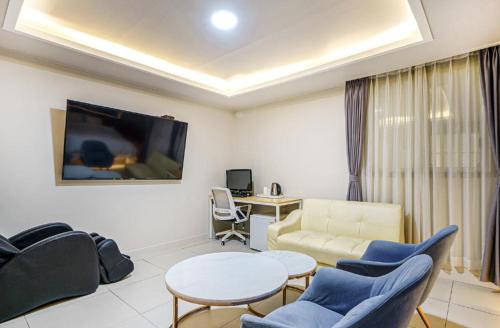 a living room with a couch and a table and chairs at Gwangju Yeogijoa Hotel in Gwangju