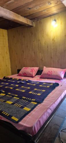 a large bed in a room with wooden walls at Blabla House Himachal in Pulga