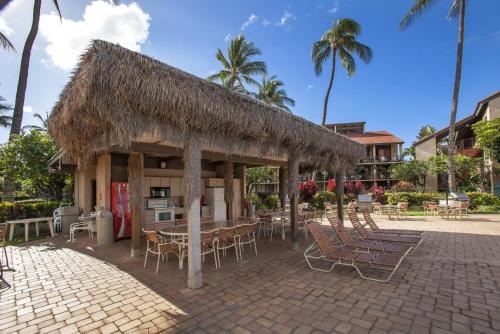 a restaurant with chairs and tables and a straw roof at Luana Kai C104 condo in Kihei