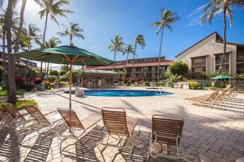 a group of chairs with an umbrella and a pool at Luana Kai C104 condo in Kihei