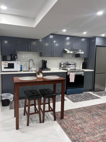 a kitchen with black cabinets and a wooden table and stool at Private 2bedroom Unit, Free Parking, Free from Smoke & Pet, Self-Check IN in Pickering