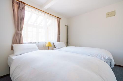 two white beds in a room with a window at Rusutsu Powder Lodge in Rusutsu