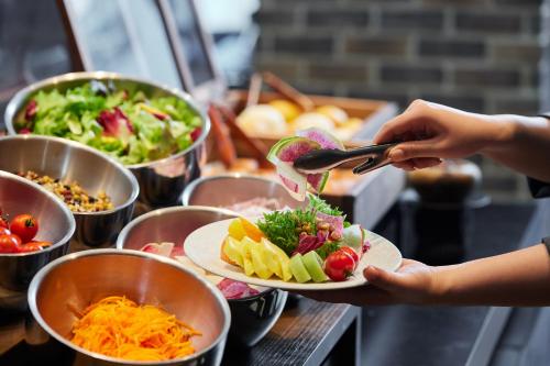 a person holding a plate of food on a buffet at SHIBUYA STREAM HOTEL formerly Shibuya Stream Excel Hotel Tokyu in Tokyo