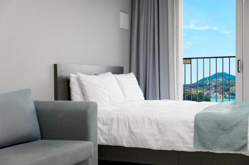 a bedroom with a bed and a chair and a window at Yeosu Stay and Park in Yeosu