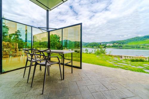 a table and chairs on a patio with a view of a river at Gapyeong Pension The Square 24 Spa Pension in Gapyeong
