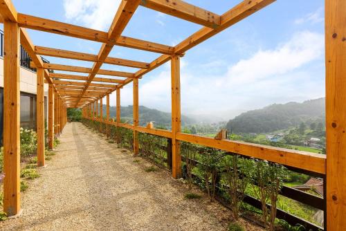 un passaggio in legno con vista sulle montagne di Gapyeong V Courtyard Pension a Gapyeong