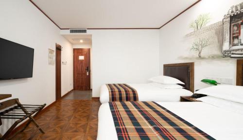 a hotel room with two beds and a flat screen tv at Nost algia Hotel Beijing Tiananmen Square & Qianmen Subway St ation 时光漫步酒店 北京天安门广场前门地铁站店 Free laundry service in Beijing