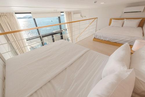 a bedroom with two beds and a large window at Aramer Spa Pension in Yeosu