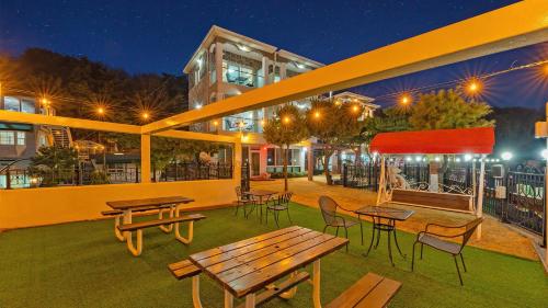 a patio with picnic tables and chairs at night at Propose 1st Pension Ganghwa in Incheon