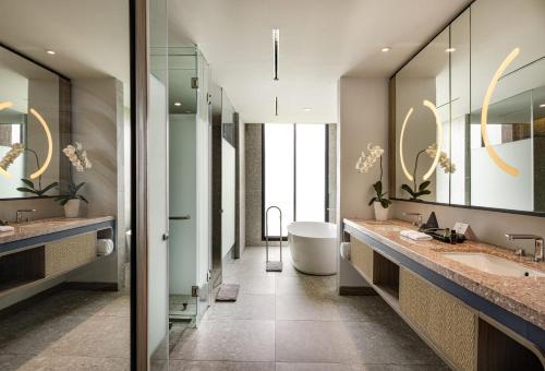 a bathroom with two sinks and a tub and mirrors at Hotel Santika Premiere Linggarjati - Kuningan in Kuningan