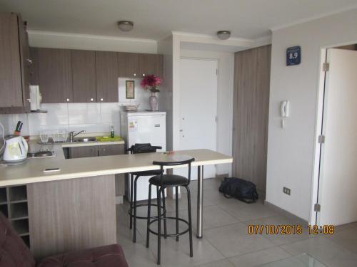 a kitchen with a counter and two bar stools at Departamentos Parque Costanera in Antofagasta