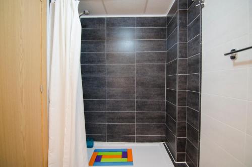 a bathroom with a tiled shower with a shower curtain at Residencial Linnea Sol by Mar Holidays in Playas de Orihuela
