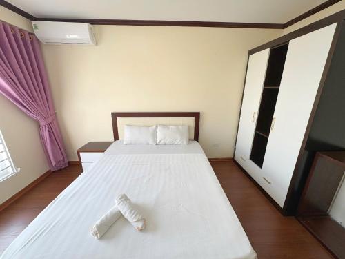 a bedroom with a white bed with a pair of slippers at Homestay Hạ Long NewLife in Kon Rung (1)