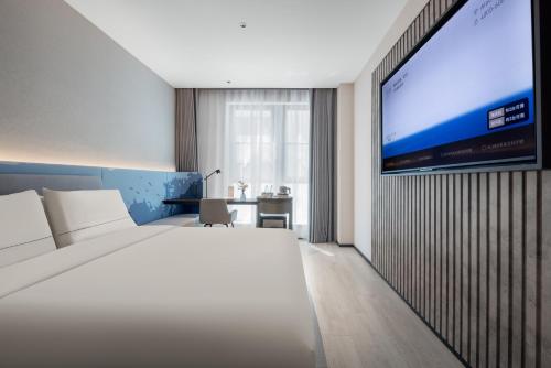 a hotel room with a bed and a flat screen tv at Atour Light Hotel Shanghai The Bund East Jinling Road in Shanghai