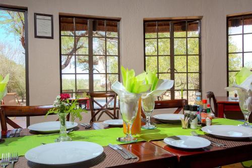 a table with plates and vases on top of it at Mvuradona Safari Lodge in Marloth Park