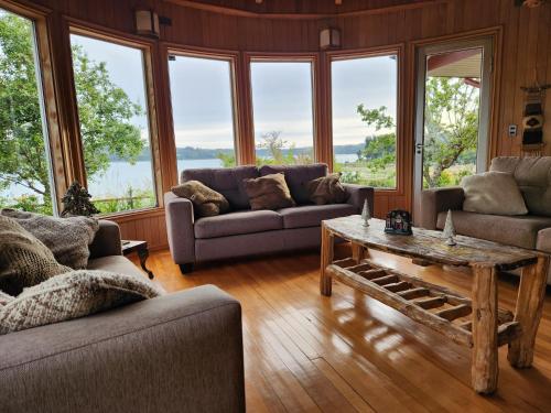 a living room with couches and a table and windows at Casa Bordemar in Castro