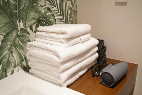 a stack of towels on a counter next to a sink at Softlight Inn Asakusa Tokyo in Tokyo