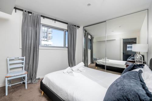 a bedroom with a mirror and a bed and a chair at Chic 1-Bedroom Retreat in Greenway in Tuggeranong