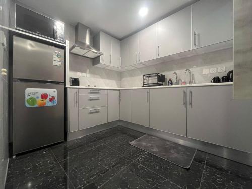 a kitchen with white cabinets and a stainless steel refrigerator at Leanitai luxury 1-BR Apartment-203 at Qatif شقة فاخرة بغرفة نوم واحدة in Tārūt