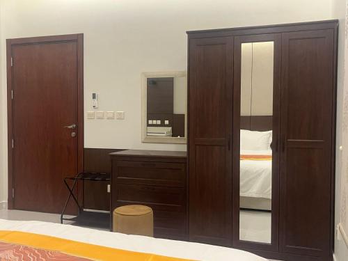 a bedroom with a wooden cabinet and a mirror at Leanitai luxury 1-BR Apartment-203 at Qatif شقة فاخرة بغرفة نوم واحدة in Tārūt