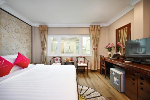 una camera da letto con un letto, una scrivania e una televisione di Pink Boutique Ben Thanh Hotel ad Ho Chi Minh