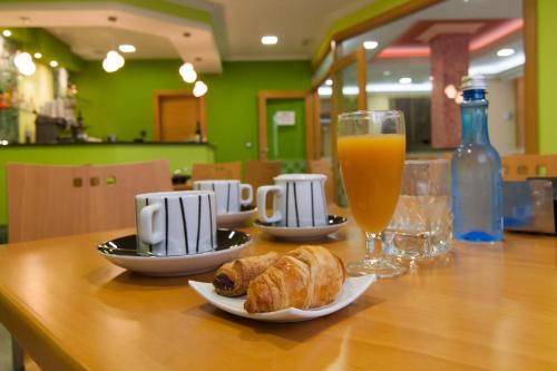a table with two plates of croissants and a glass of orange juice at Pontus Veteris in Sanxenxo