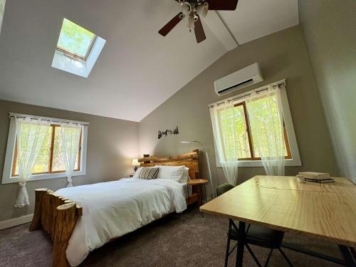 a bedroom with a bed and a table and windows at Walking Distance to the Beach Cabin with AC in Arrowhead Lake