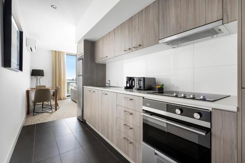 a kitchen with wooden cabinets and a stove top oven at Quest Chatswood in Sydney