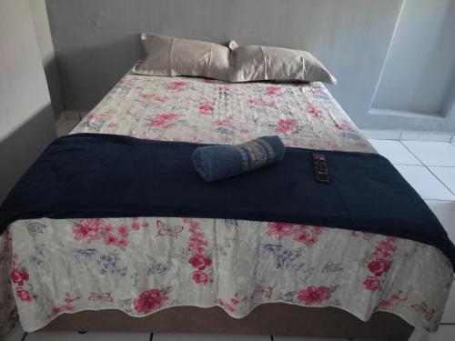 a bed with a blanket and pillows on it at Casa no Centro da Cidade ao lado dos hospitais in Vitória da Conquista