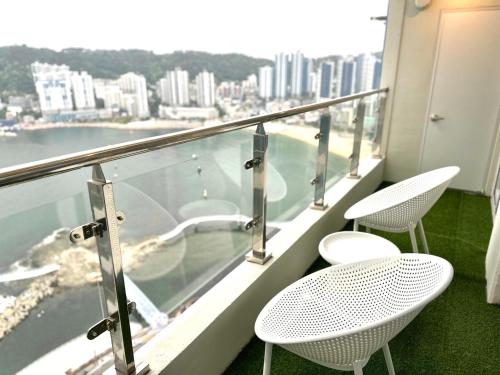 a balcony with two chairs and a view of the water at THE DECEMBER STAY Busan Songdo Ocean Terrace in Busan