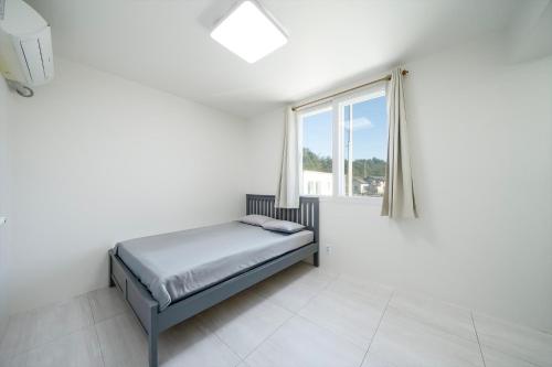 a white bedroom with a bed and a window at Yangyang Jangyo House Dog Pool Villa Pension in Yangyang