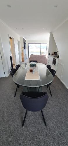 a living room with a glass table and chairs at Kakianau Retreat, Luxury Waterfront Apartments in Portobello