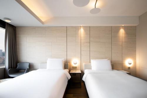 two beds in a hotel room with white sheets at Eliena Hotel Seoul Gangnam in Seoul