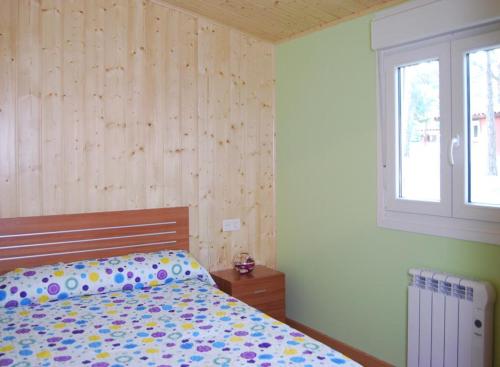 a bedroom with a bed with polka dot sheets and a window at Camping Urbion in Abejar