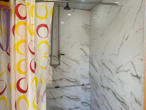 a shower curtain in a bathroom with white marble walls at Иззат in Akchiy