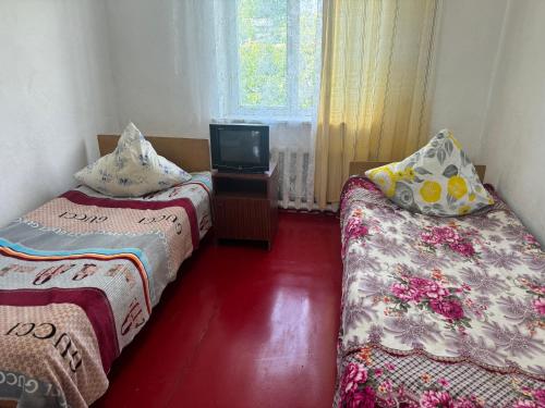 a room with two beds and a tv in it at Иззат in Akchiy