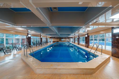 a large swimming pool in a large room with windows at Квартира в Радуга Плюс in Chon-Sary-Oy
