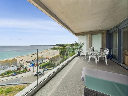 a balcony with a table and chairs and a view of the beach at Luxury 3-bed apartment, with direct beach access, free parking & sea views ! in Falmouth