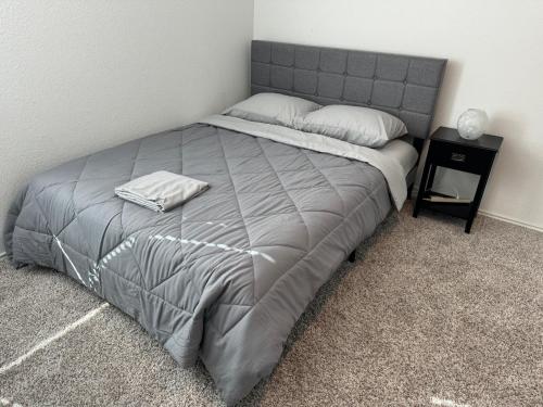 a bedroom with a bed with a gray blanket and a night stand at The Gentle Rest in Round Rock