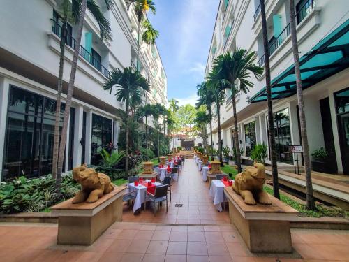 a row of tables and chairs in a courtyard with palm trees at Tara Angkor Hotel in Siem Reap