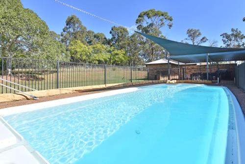 an empty swimming pool with a canopy and a fence at Blaxlands Kangaroo Homestead with Hot Tub walk to Concerts and Wineries in Pokolbin