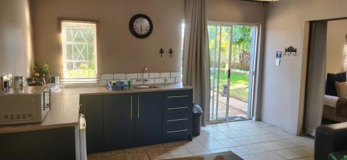 a kitchen with a sink and a clock on the wall at Kuruman Garden Cottages unit 2 in Kuruman