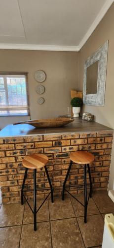 a counter with two stools in a room at Kuruman Garden Cottages unit 2 in Kuruman