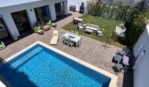 a swimming pool next to a patio with a table and chairs at Maison de Chacha in Hammamet