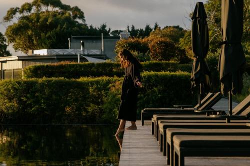 a woman walking down a boardwalk next to a pool at Jackalope Hotel in Merricks North
