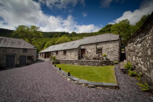 un antiguo edificio de piedra con un patio de césped delante de él en Plasglasgwm, en Betws-y-coed