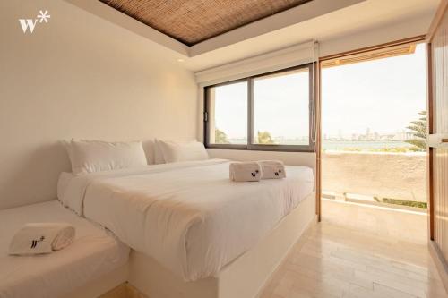 Un dormitorio blanco con una cama grande y una ventana grande. en Amazing 4BR Villa with Ocean View in Castillogrande, en Cartagena de Indias