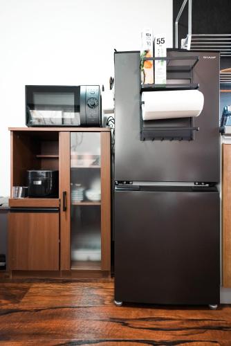 a kitchen with a stainless steel refrigerator and a microwave at Takumi Renovated House Osaka Hirakata with Free Parking in Hirakata
